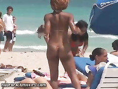 Жёлтые стринги  пляжной девочки загорающей топлесс