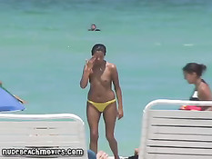 Жёлтые стринги  пляжной девочки загорающей топлесс