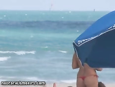 Жёлтые стринги  пляжной девочки загорающей топлесс