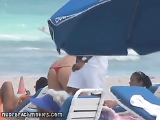 Жёлтые стринги  пляжной девочки загорающей топлесс