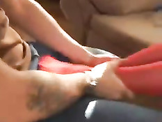 Девчонка в красных чулочках и сетчатом боди умеет дрочить ногами