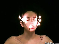 Втыкает иголки в обнажённую девку и капает расплавленным воском