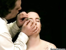 Втыкает иголки в обнажённую девку и капает расплавленным воском