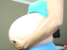 Беременная девушка мажет кремом и массирует свой большой живот