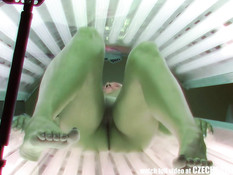 Молодая блондинка с татуировкой на пояснице загорает в солярии