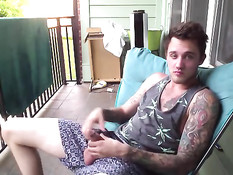 Симпатичный молодой гей с татуировками дрочит член на балконе