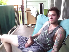 Симпатичный молодой гей с татуировками дрочит член на балконе