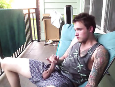 Симпатичный молодой гей с татуировками дрочит член на балконе