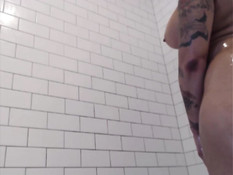 Татуированная девушка с большой грудью принимает горячий душ