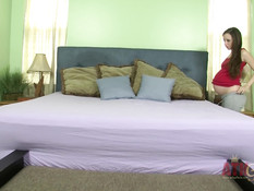 Сисястая беременная шатенка лёжа на кровати мастурбирует вибратором